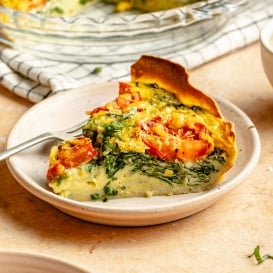 slice of tortilla quiche with tomato, spinach, and basil on a plate