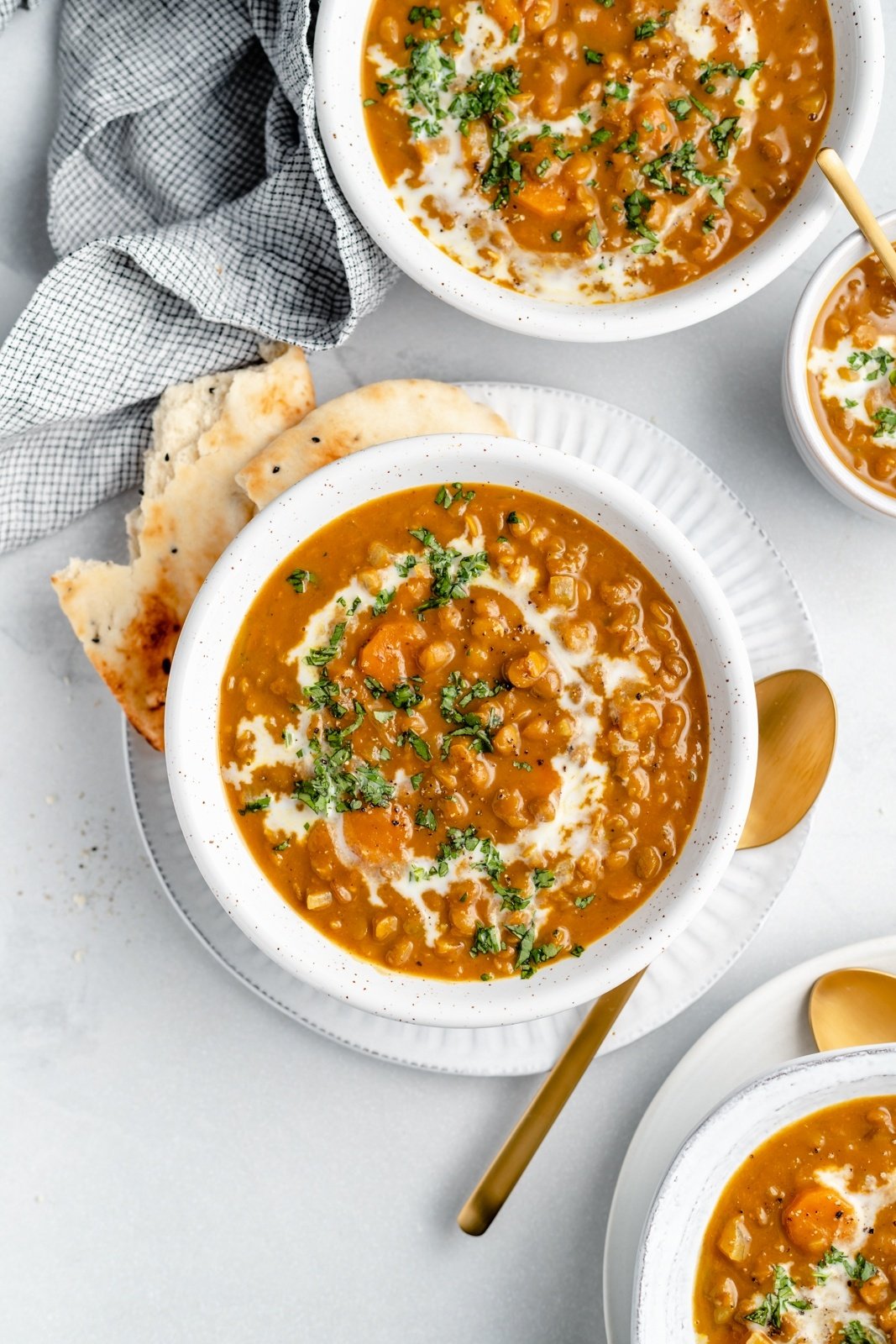 pumpkin lentil soup in a bowl with a spoon and pita bread