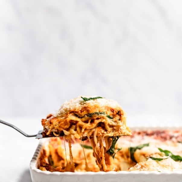 lifting a slice of vegetarian pumpkin lasagna out of a pan