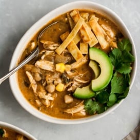 healthy white chicken chili in a bowl topped with tortilla strips and avocado slices