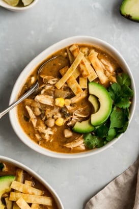 healthy white chicken chili in a bowl topped with tortilla strips and avocado slices