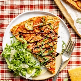 slice of a tomato zucchini tart on a plate with an arugula salad